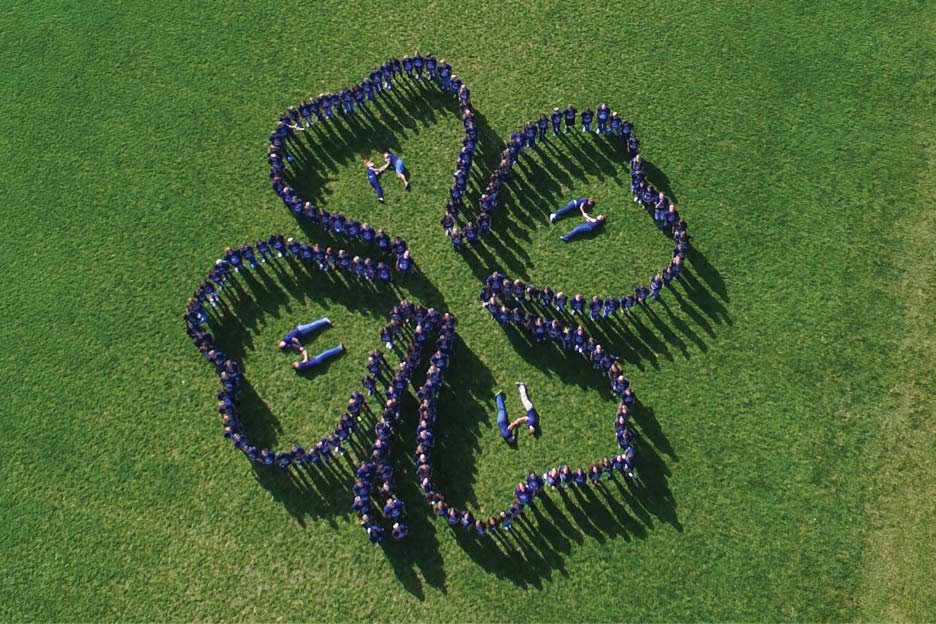 kids on a grass field forming a 4-H clover.